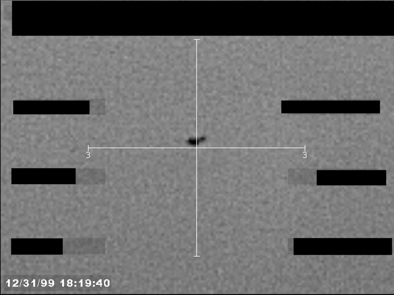 Redacted sensor image with a targeting reticle centered on an object.